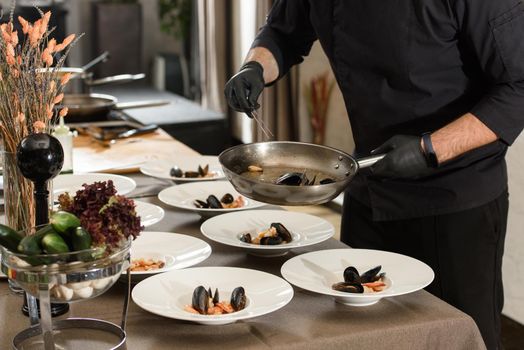 chef prepares set of carrot cream soup with seafood in a restaurant