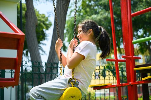 happy little hispanic girl child having fun to playing in the park in summer time with smile and laughing healthy, Adorable girl having fun on a swing on summer. happy vacation lifestyle concept