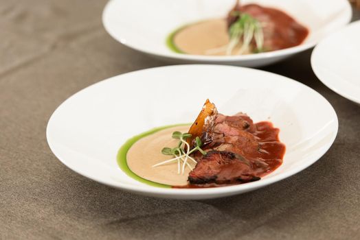 veal tenderloin with fried mashed potatoes and micro green.