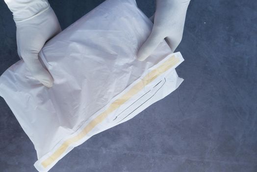 hand in latex gloves holding white paper bubble envelope for postal ship