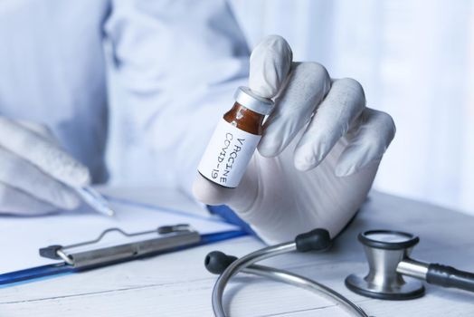 hand in gloves holding coronavirus, vaccine.