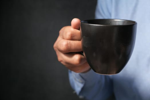 close up of man hand holding yellow color mug .