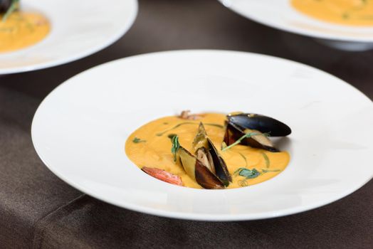 carrot cream soup with seafood on a table in a restaurant.