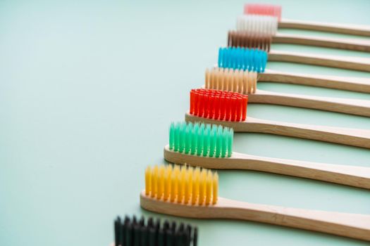 A set of Eco-friendly antibacterial toothbrushes made of bamboo wood on a light green background. Environmental care trends.