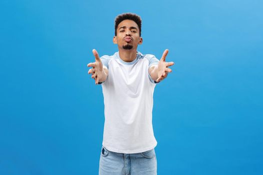 Come and give me kiss. Portrait of passionate romantic and pleased african american guy with beard pulling hands towards camera and folding lips in mwah wanting cuddle, expressing affection.