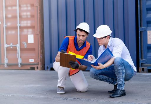 Foreman and container worker sit and discuss together about data in their document.