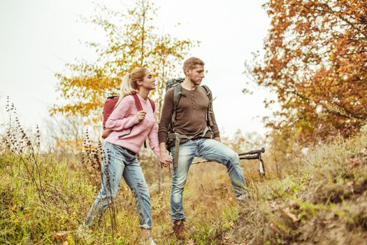 Tourists wading through the hills holding hands. A young couple of people in love checks the strength of their relationship while traveling in the wild. Hiking concept.