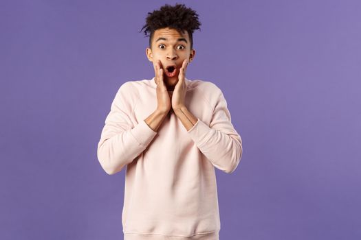 Oh my gosh. Portrait of amazed, speechless excited hispanic guy staring overwhelmed at something stunning, watching incredible performance, react shocked and amazed, purple background.