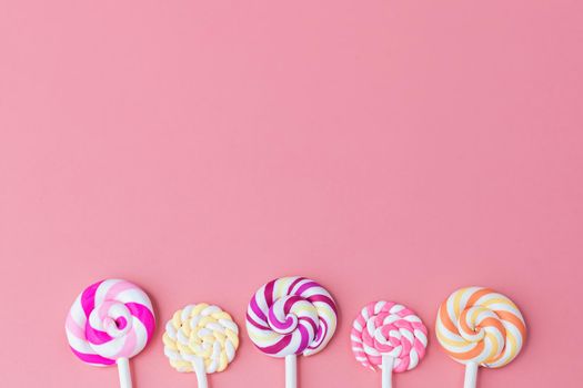 Delicious colourful of lollipop on pink background with copy space for snack food concept