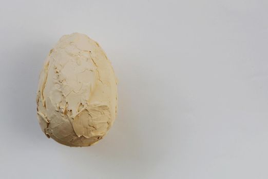 Artificial unfinished egg covered with a primer on a white homemade background.