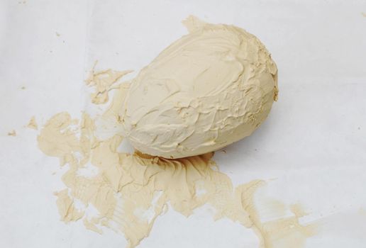Artificial egg in the process of priming and painting on a paper background.
