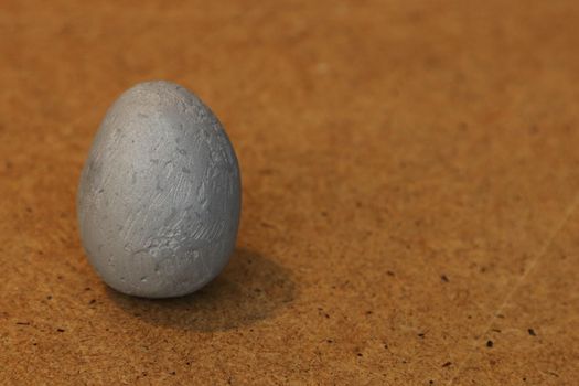 Artificial stone egg on a brown wooden background.