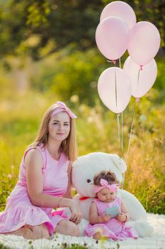 mother and daughter in pink dresses and with pink balloons in nature