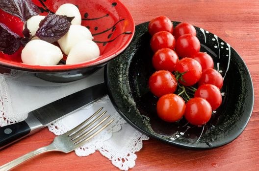 Ingradients for Italian caprese salad with fresh basil leaves, tomato and mozzarella on red wooden table. Overhead view. From series Natural organic food