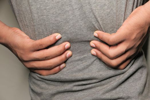young man in blue shirt suffering back pain