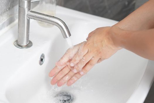 Hands washing for prevention of novel Coronavirus Disease 2019 or COVID-19 . People wash hands at bathroom sink to clean the virus infection.