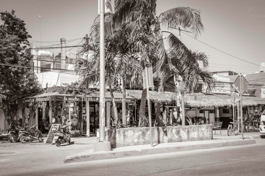 Tulum Mexico 02. February 2022 Old black and white picture of driving thru typical colorful street road and cityscape with cars traffic palm trees bars and restaurants of Tulum in Mexico.