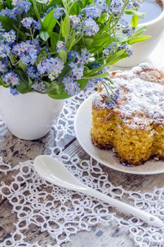 Polenta cake with cup of Coffee. Near forget me nots on rustic wooden table.