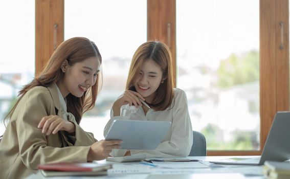 Two beautiful young asian businesswoman working together using digital tablet at office..