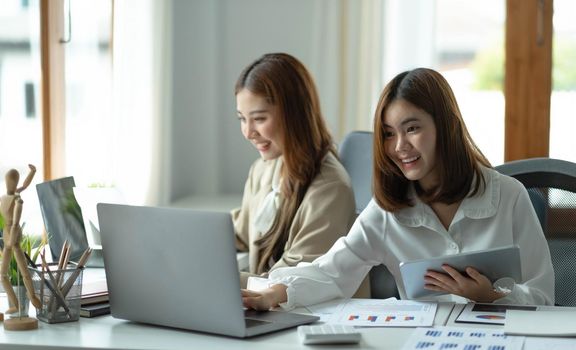 Two beautiful young asian woman working in office on laptop computer..