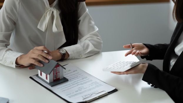 Real Estate concept, Agent holds calculator for present price for loan investment chart graph documents and calculating table payment to customer.