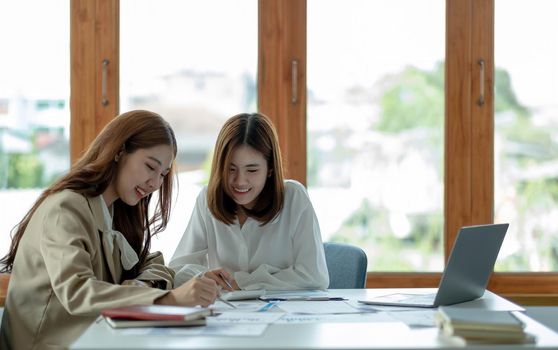 Young Asian businesswoman work together to analysis from work at the office..