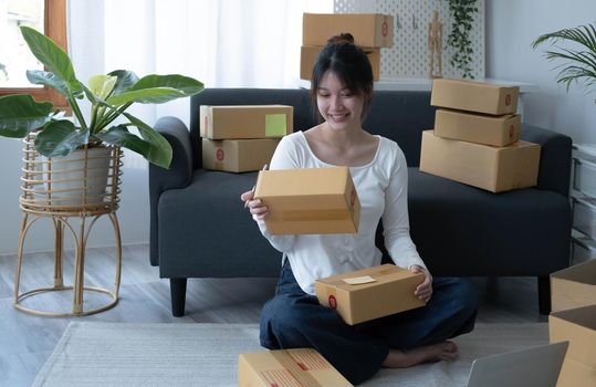 Young asian entrepreneur, Teenager online business owner work at home, Women packing product that customer order from the website, delivered as a package, use services parcel delivery shipping company.