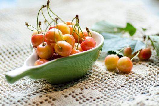 Ripe cherries in the cup on knitted tablecloth