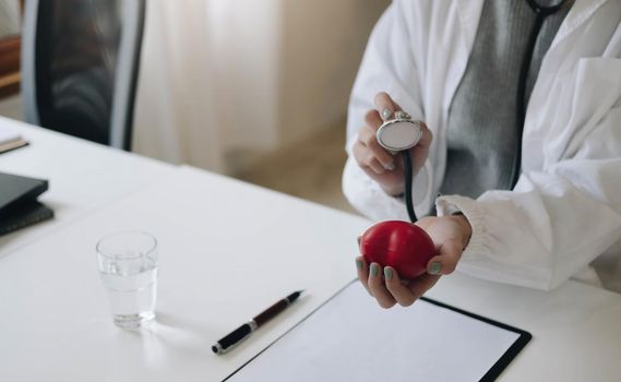 Woman doctor hands holding stethoscope to checking red heart model,Good health good life,World heart dayHealth care checking concept.