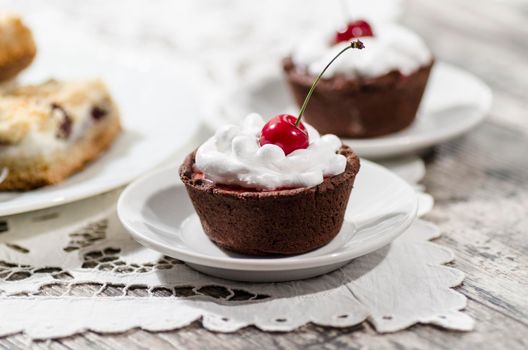 Chocolate dessert decorated with whipped cream and a cherry