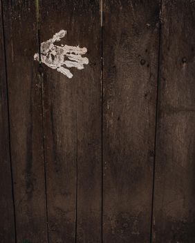 white palm and fingerprint on the Old shabby wooden grey boards. fence. background. texture. Weathered painted plank. Vintage. wall. paint. Hand in white paint.