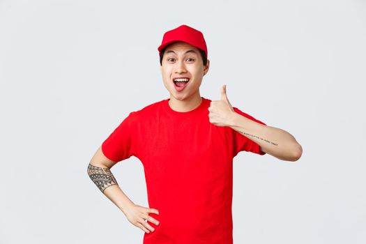 Very good delivery company. Cheerful asian courier in uniform, red cap and t-shirt, encourage shop safely and use company service for ordering and receiving parcels, thumb-up in approval.