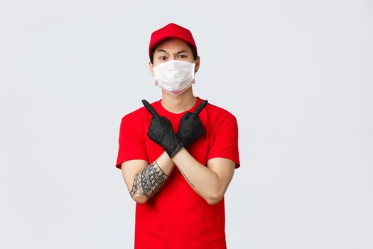 Indecisive asian delivery guy point sideways at upper right and left variants, two choices of promo offers, frowning uncertain, wear uniform. Courier help make decision, quarantine shopping concept.