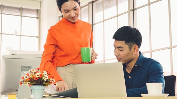 Two business people talk project strategy at office meeting room. Businessman discuss project planning with colleague at modern workplace while having conversation and advice on financial data report.