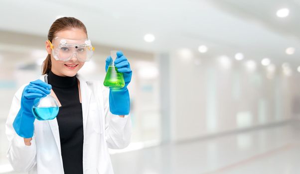 Portrait of young happy scientist or chemist holding test tube in laboratory. Chemical or medical technology research and development concept.
