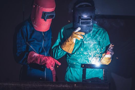 Metal welding steel works using electric arc welding machine to weld steel at factory. Metalwork manufacturing and construction maintenance service by manual skill labor concept.
