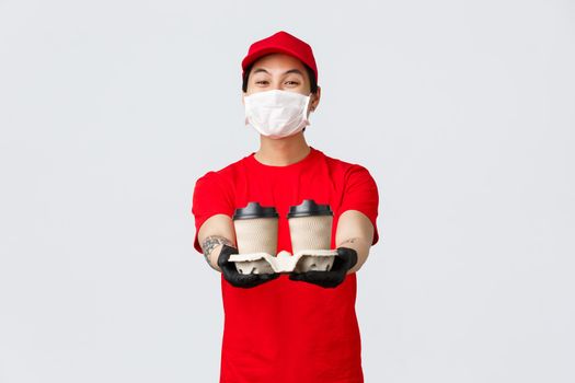 Friendly smiling asian delivery man working during covid 19 pandemic, bring your food order doorstep, extend hands with coffee from local cafe you ordered application or online.