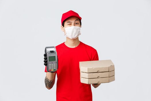 Contactless delivery, safe purchase and shopping during coronavirus concept. Cheerful fast-food employee or courier in red uniform cap, t-shirt, bring POS terminal with pizza to client, bring order.