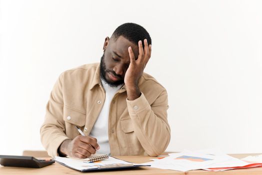 Problems in the household budget during the crisis. Young black sad man looking through mortgage papers or economic reports, upset and angry