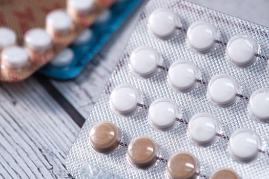 birth control pills on wooden background, close up .