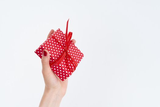 beautiful woman hands holding a red present with ribbon, hands with red nail polish gloss shine, concept on white background copy space