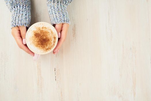 Top view hands holding cup of hot chocolate, blue cozy sweater, beautiful pink manicure, home style, autumn morning, close up, copy space
