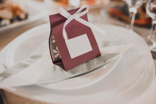 Card with the inscription of the guest's name for serving on the festive table on a white plate