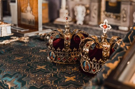 Two golden crowns in precious stones stand on the table in the church.