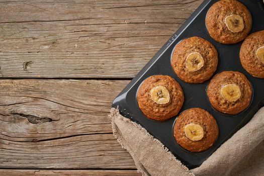 Banana muffin in tray, top view, copy space. Cupcakes on old linen napkin, rustic wooden table, a breakfast with cake