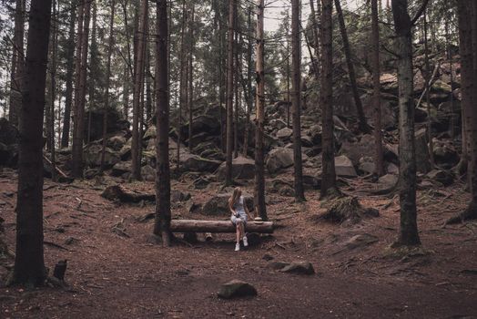 Slavic tanned fair-haired young girl with a boater hat on nature. Traveler tourist in a dark forest. constant tone of clothes. dark brown background