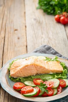 Steam salmon and vegetables, Paleo, keto, fodmap diet. Side view, vertical. Healthy diet concept, blue plate on old rustic wooden table