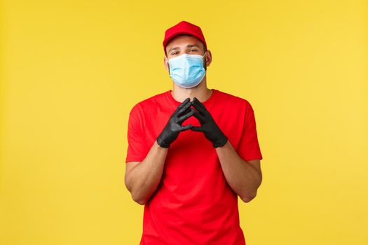 Express delivery during pandemic, covid-19, safe shipping, online shopping concept. Smart and creative courier in red uniform, gloves and medical mask, scheming, steeple fingers sly.