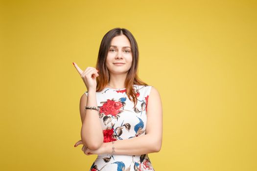 Side view studio portrait of stylish attractive young woman looking away and holding finger. Sudactive feminine model in black with make up plump lips and big eyes holding hand. Concept of style.