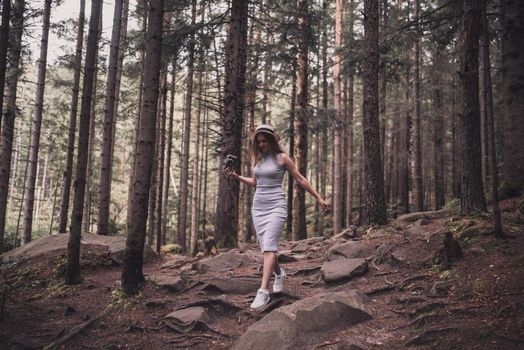 Slavic tanned fair-haired young girl with a boater hat on nature. Traveler tourist in a dark forest. constant tone of clothes. dark brown background